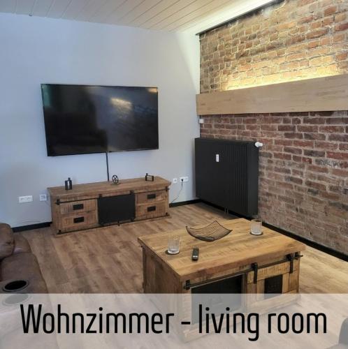 a living room with a television and a brick wall at Lokschuppen - Backstein-Loft in Bad Oeynhausen