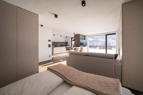a bedroom with a bed and a kitchen with a window at Trutscher Häusl in Villnöss - Chalet in den Dolomiten mit Blick auf die Geisler in Funes