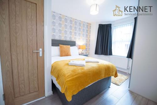 a bedroom with a bed with a yellow blanket on it at Franklin Lodge in Reading