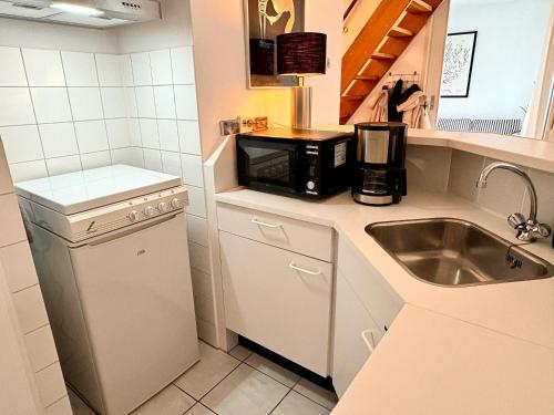 a small kitchen with a sink and a microwave at De Korre 10 in Callantsoog