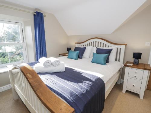 a bedroom with a bed with blue pillows and a window at Tyddyn Goronwy in Dyffryn