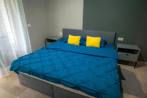 a bedroom with a blue bed with yellow pillows at RMR Luxury Apartaments in Timişoara