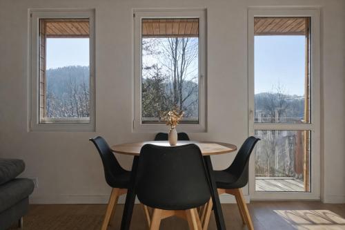 a dining room with a table and three windows at Domek na Nowej Osadzie in Wisła
