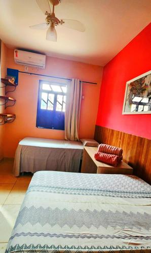 a bedroom with red walls and a bed and a window at Escapada do Sonho in Lençóis