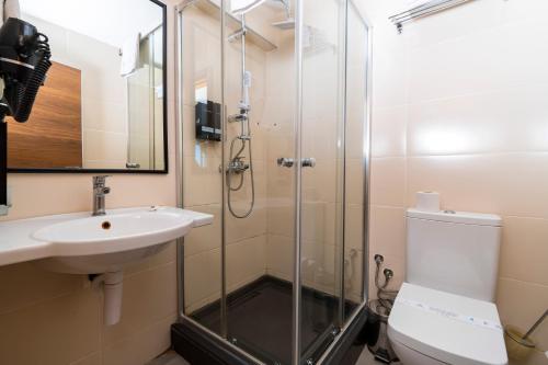 a bathroom with a shower and a toilet and a sink at Mimoza Beach Hotel in Yenibosazici