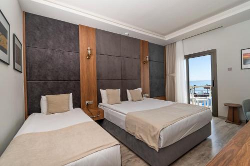 a hotel room with two beds and a balcony at Mimoza Beach Hotel in Yenibosazici