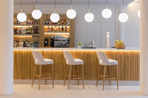 a bar with white chairs and a wooden counter at Aluasun Lago Rojo - Adults recommended in Torremolinos