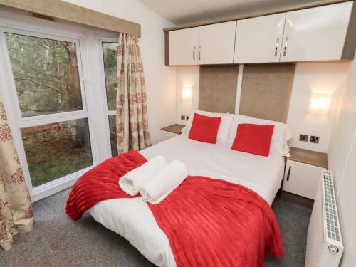 a bedroom with a bed with red pillows and a window at Chloe's Cabin in Morpeth