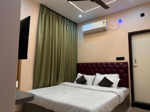a bedroom with a bed and a television on the wall at Hotel Maple Lawn in Guwahati