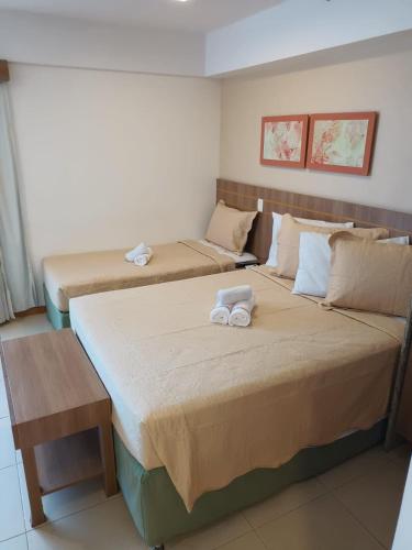 two beds in a room with towels on them at Apart no Hotel Saint Moritz n° 810 in Brasília