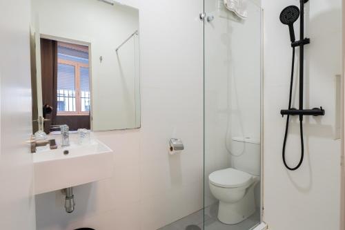 a white bathroom with a toilet and a sink at Hostal La Muralla in Seville
