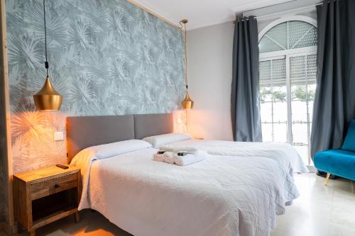 a bedroom with two beds and a blue wall at Hostal La Muralla in Seville