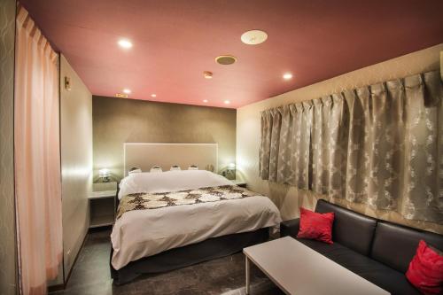 a bedroom with a large bed and a couch at Hotel Flower Style koriyama tenri in Tenri