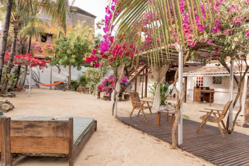 a patio with chairs and trees with pink flowers at casa jasmin in Jericoacoara