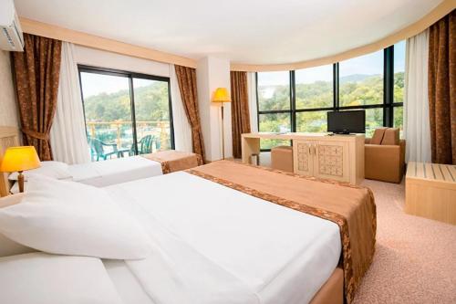 a hotel room with two beds and a large window at Alder Resort Hotel -Ultra All Inclusive in Kemer