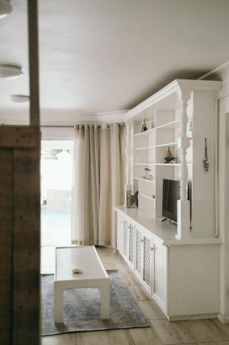a white living room with a tv and a table at Summer House B&B in Gqeberha