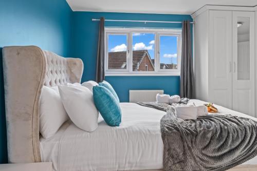 a bedroom with a white bed with blue walls and a window at Ideal Budget Contractor Stay - 4B Home w en-suites in Great Sankey