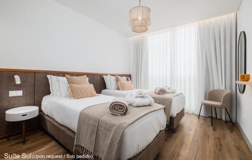 a bedroom with two beds and a chair at Mónaco Suites & Garden in Ponta Delgada
