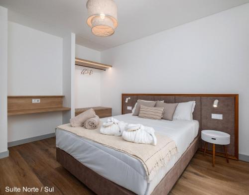 a bedroom with a large bed with towels on it at Mónaco Suites & Garden in Ponta Delgada