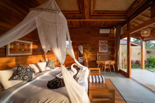 a bedroom with a bed with mosquito net at The Patra Villa Sebatu by Dhananjaya Hospitality in Tampaksiring