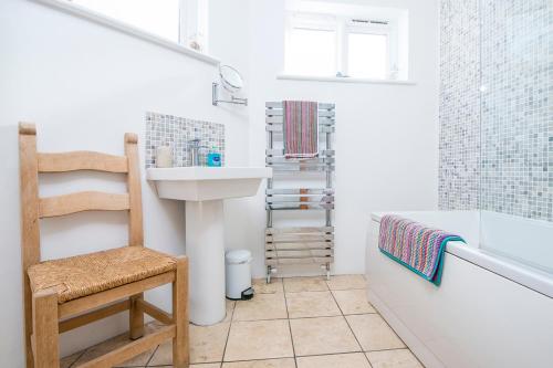 a bathroom with a sink and a tub and a chair at Ty Draw in HAW