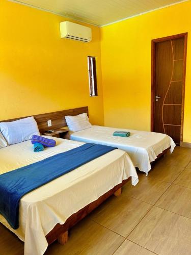 two beds in a room with yellow walls at Vila Itacimirim in Itacimirim