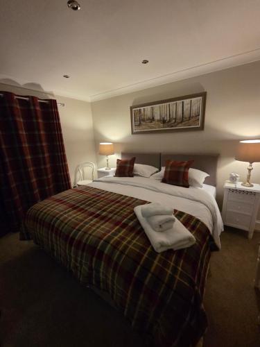 a bedroom with a bed with a blanket and two lamps at The Cairn at North Lodge, Rural Guest Suite in Kirriemuir
