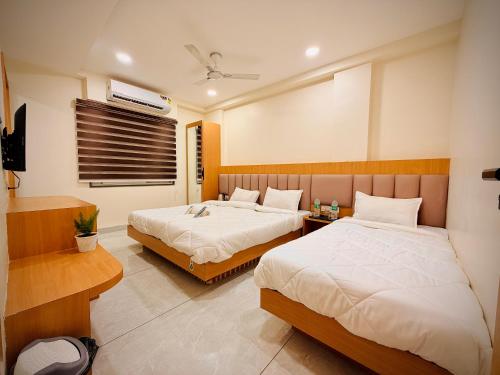 a hotel room with two beds and a television at Hotel Kavita Inn in Ujjain