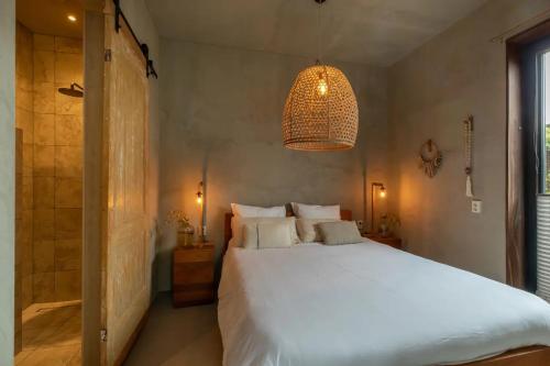 a bedroom with a large white bed and a chandelier at PUUR aan de Zeeuwse kust in Wemeldinge