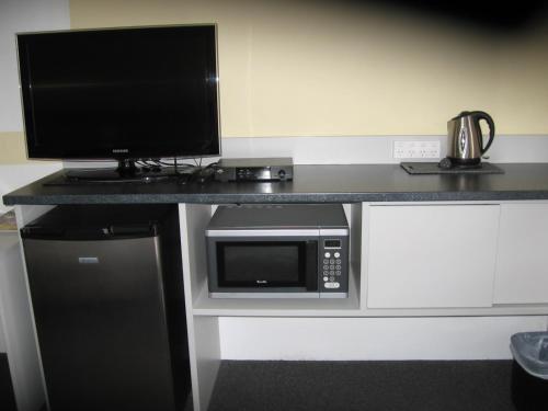 einen Schreibtisch mit einer Mikrowelle und einem TV in der Unterkunft Darlot Motor Inn in Horsham