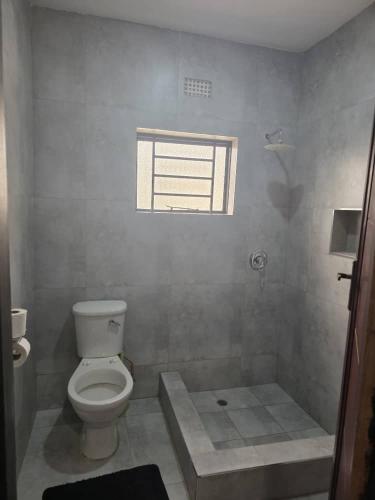 a bathroom with a toilet and a window at wamis Fully serviced apartments in Solwezi