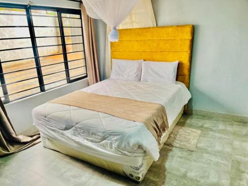 a bedroom with a large bed with a yellow headboard at wamis Fully serviced apartments in Solwezi