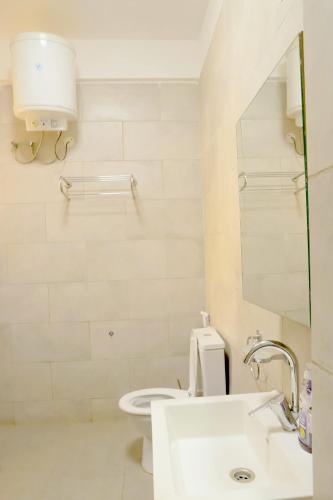 a white bathroom with a toilet and a sink at EKay's Space Najjera1 in Namugongo