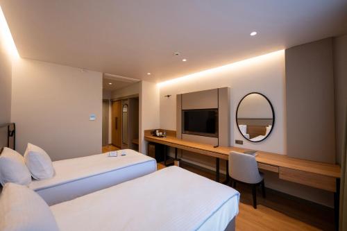 a bedroom with two beds and a desk and a mirror at Reiwa Business Hotel in Osmaniye