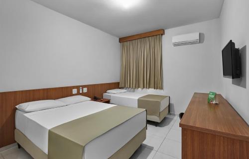 a hotel room with two beds and a television at Hotel Nacional Inn Limeira in Limeira