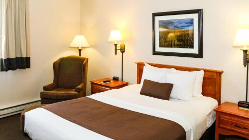 a hotel room with a bed and a chair at Studio 6 - Minot, ND in Minot