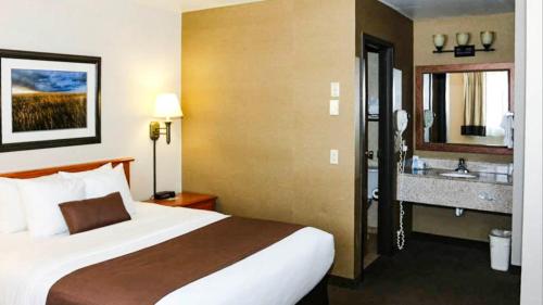 a hotel room with a bed and a sink at Studio 6 - Minot, ND in Minot