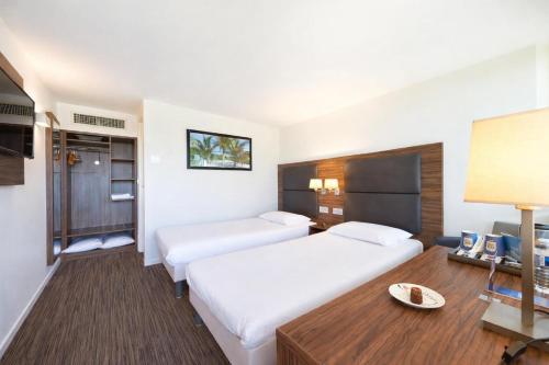 a hotel room with two beds and a table at Kyriad Bordeaux - Merignac Aéroport in Mérignac