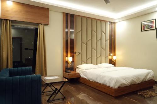 a bedroom with a bed and a blue chair at BANMALI REGENCY in Jamshedpur