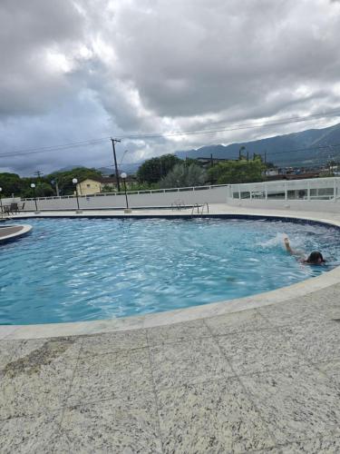 a person swimming in a swimming pool at Apartamento confortável no Centro in Bertioga