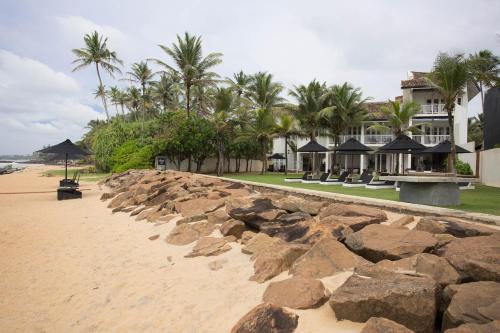 a building on a sandy beach with palm trees at Arabella on Boossa in Galle