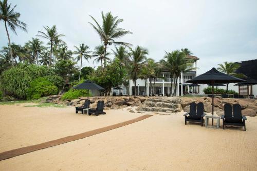 a group of chairs and umbrellas on a beach at Arabella on Boossa in Galle