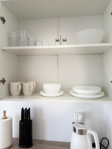 a kitchen with white shelves with dishes and a tea kettle at Dom Gościnny Ania in Wisełka