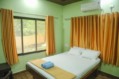 a bedroom with a bed and a window with orange curtains at Ambadnya Homestays in Dāhānu