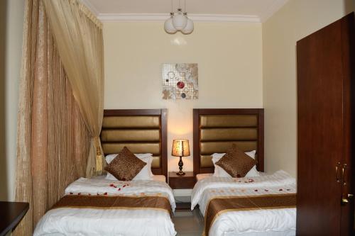 a hotel room with two beds and a lamp at Jowharet AlMaseya in Al Khobar