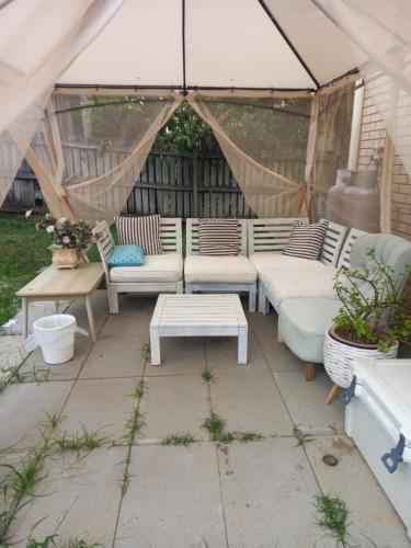 a patio with couches and a table and an umbrella at Air conditioned Holiday Dream Castle Youth Hotel in Brisbane