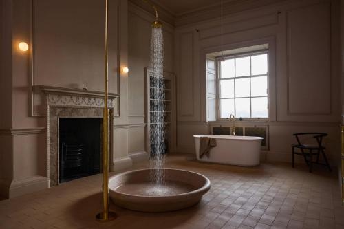 a large bathroom with a tub and a fireplace at Denton Hall in Ilkley