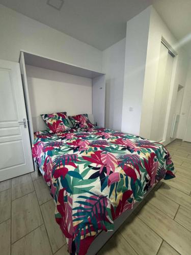 a bed with a colorful comforter in a bedroom at Le studio de Jazzy in Fécamp