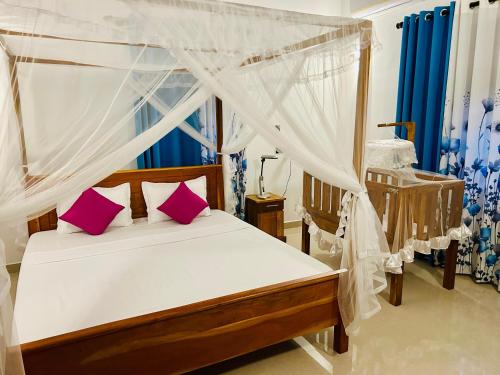a bedroom with a canopy bed with pink pillows at King Royal - Tangalle in Tangalle