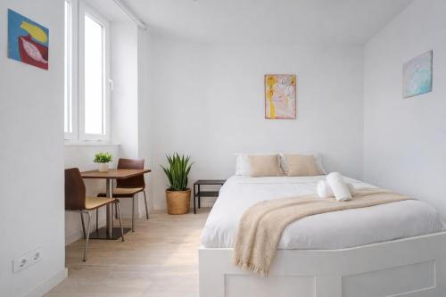a white bedroom with a bed and a table at PortoNest Downtown Suites in Porto
